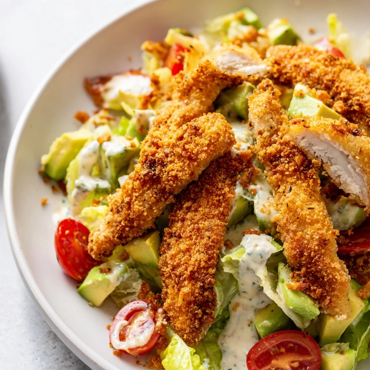 A close-up of the crispy chicken taco salad with golden, spiced chicken strips on a bed of fresh romaine lettuce.  