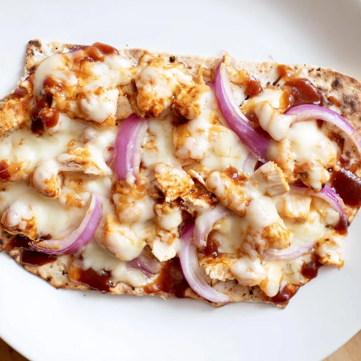 Sizzling BBQ Chicken Flatbread fresh from the oven, featuring tender chicken, sweet onions, and bubbly cheese on a golden flatbread.