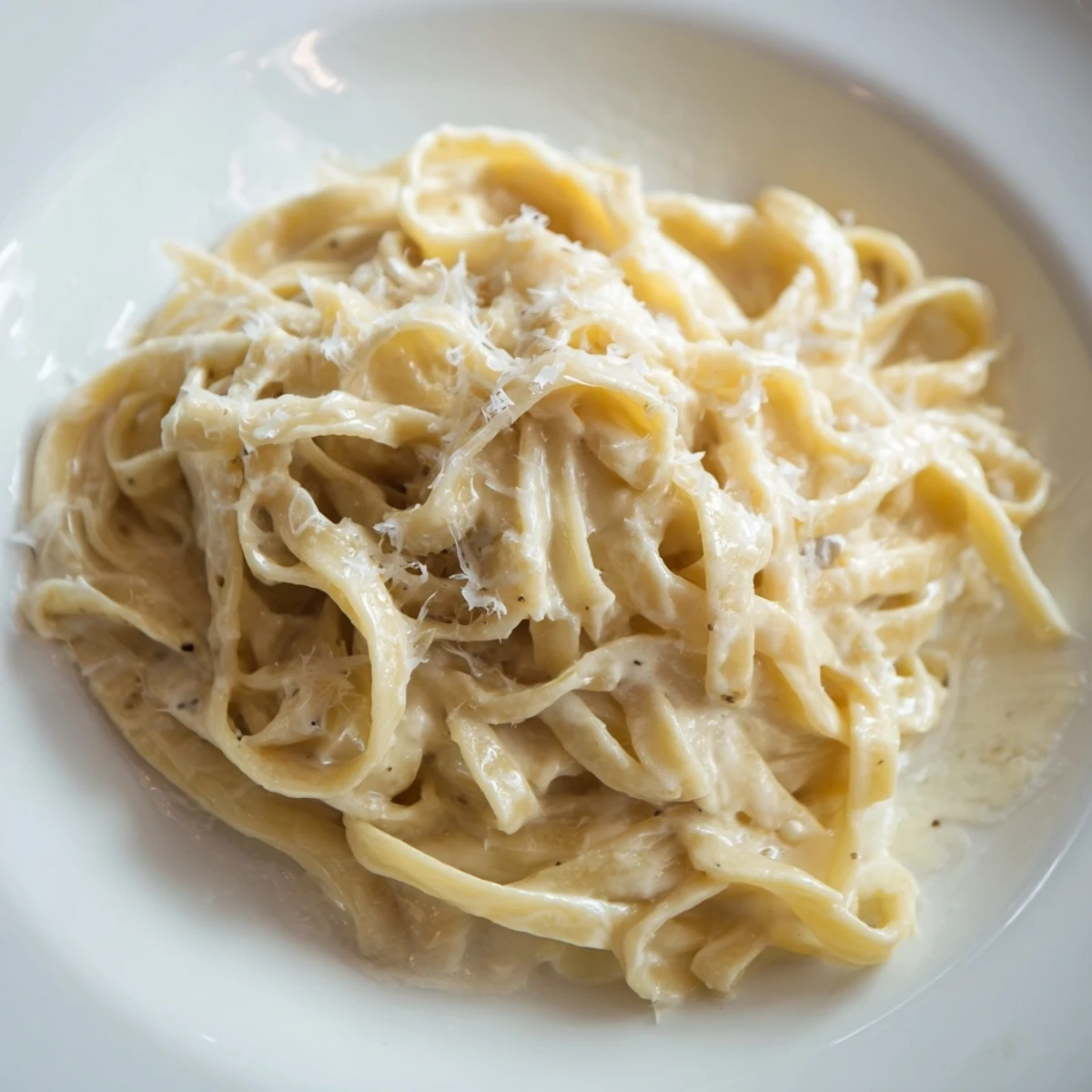 Creamy roasted garlic pasta twirls on a fork, garnished with fresh parsley.  