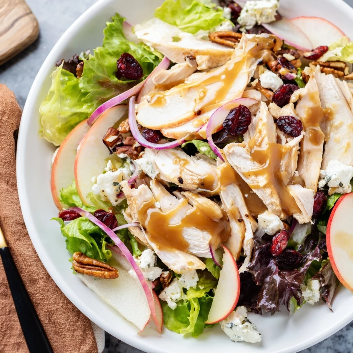A vibrant plate of Caramel Apple Chicken Salad with sliced apples, greens, and pecans, ready to serve at an autumn dinner party.