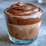 Frothy Hojicha Cortado in a clear glass, showcasing the warm brown hue and rich crema top.