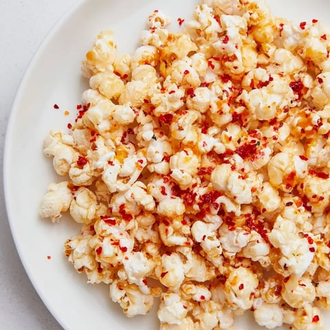 Golden, glistening hot honey butter popcorn, a perfect savory snack with a spicy kick.