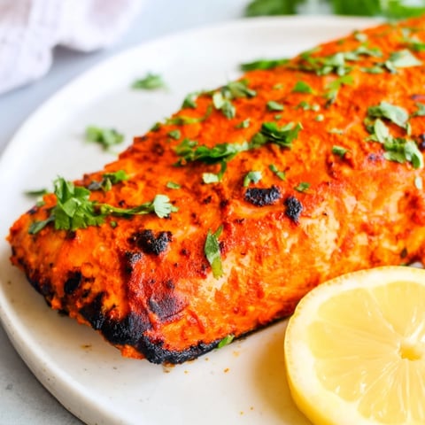 Golden-brown Indian tikka salmon glistens, ready to be served, a flavorful and healthy main dish.