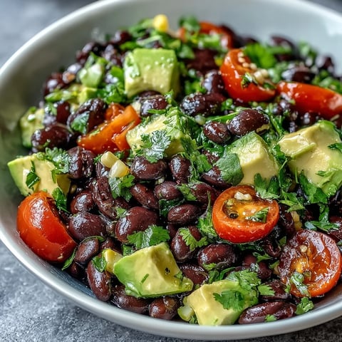 Freshly prepared Black Bean and Veggie Bowl with diced avocado, sweet corn, and cherry tomatoes in a zesty lime dressing.