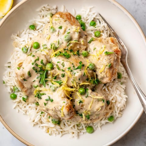 Creamy lemon chicken and rice dish with tender peas, zesty sauce, and fluffy grains.