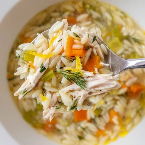 Hearty Chicken Lemon Orzo Soup with tender vegetables and orzo pasta, served steaming hot in a rustic ceramic bowl.  