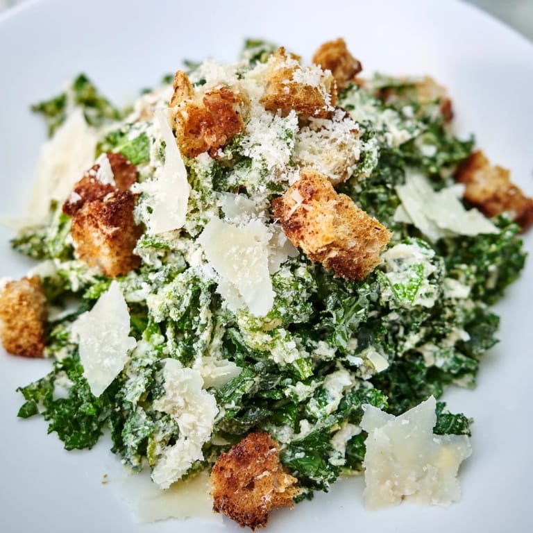 A bright image: a Kale Caesar Salad with shaved Parmesan and golden, crunchy croutons.