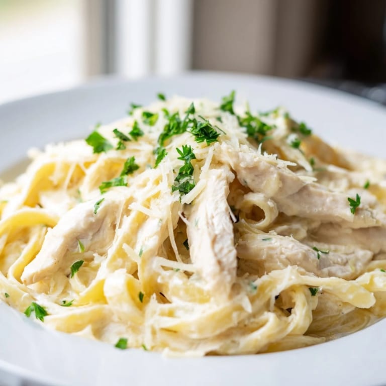 Steaming Skillet Chicken Alfredo is plated with fresh parsley, ready for an easy Italian-American weeknight dinner.