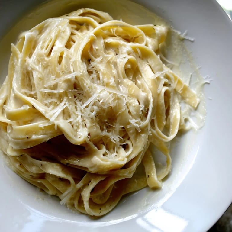 Silky roasted garlic cream sauce coats tender fettuccine in a warm skillet.  