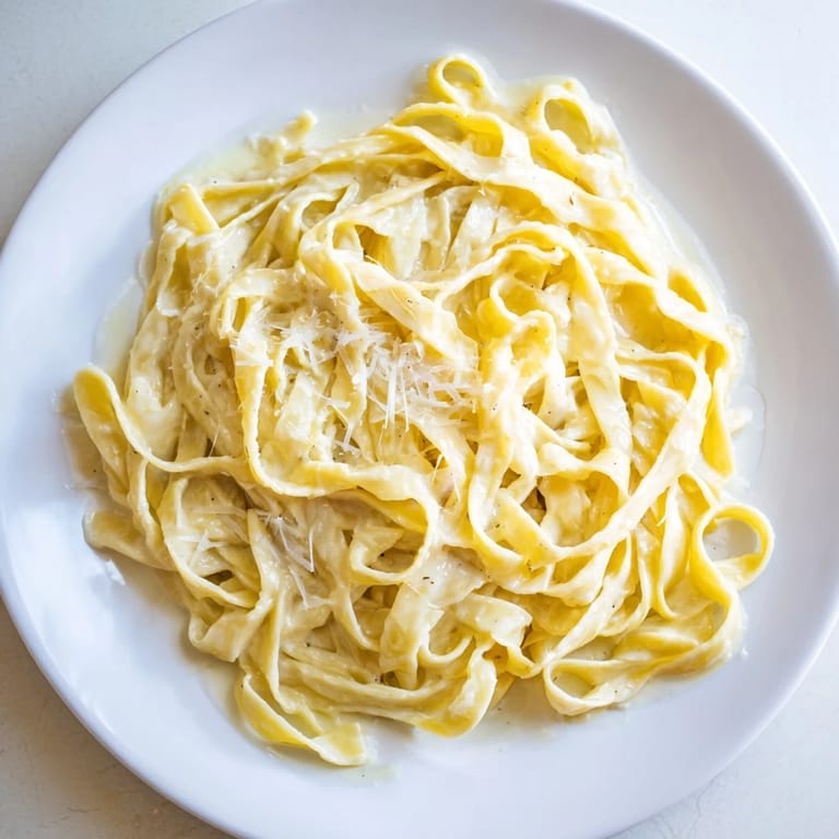 Roasted Garlic Cream Pasta steams in a bowl, topped with extra Parmesan.