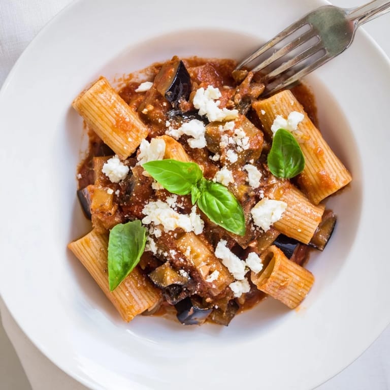 Savory Pasta Alla Norma features tender roasted eggplant, aromatic basil, and crumbly ricotta salata over perfectly cooked pasta.  