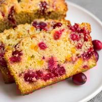 A slice of freshly baked seasonal cranberry and orange bread, bursting with vibrant flavors.