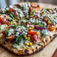 Vibrant St. Patrick's Day rainbow veggie flatbread pizza with colorful vegetables arranged in a festive arc on naan, topped with melted mozzarella and feta cheese.