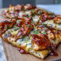 A smoky BBQ chicken flatbread pizza with melted mozzarella, red onions, and bell peppers, perfect for a quick dinner.