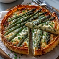 Golden asparagus ricotta tart with crisp puff pastry, creamy lemon-infused ricotta, and fresh spring asparagus spears.  